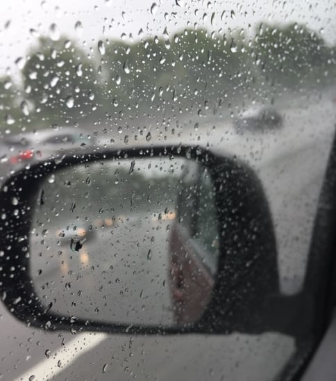 Cars side mirror with view of driving in rain