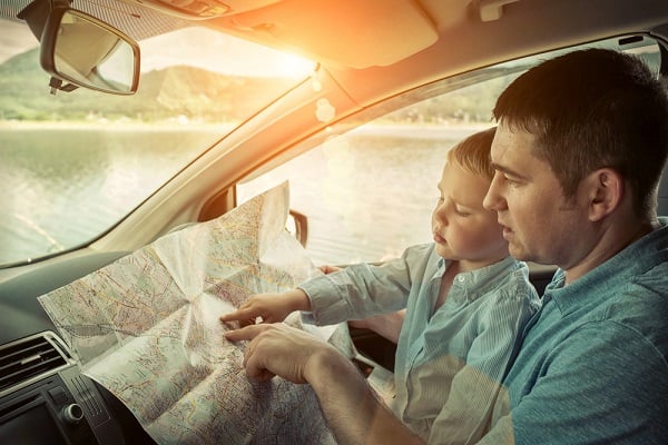 Father with small son looking a map in car