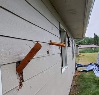 Pieces of wood embedded in side of house from severe weather
