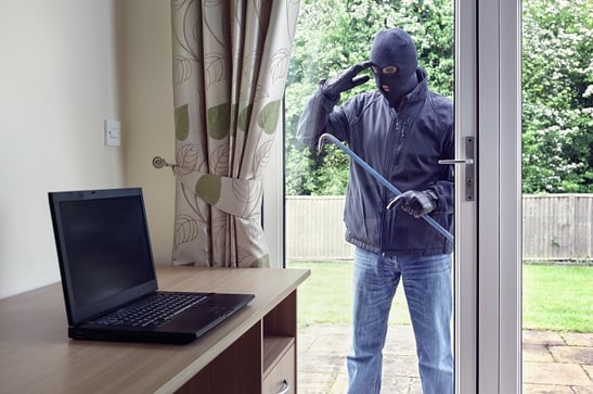 burglar peering in home window at laptop